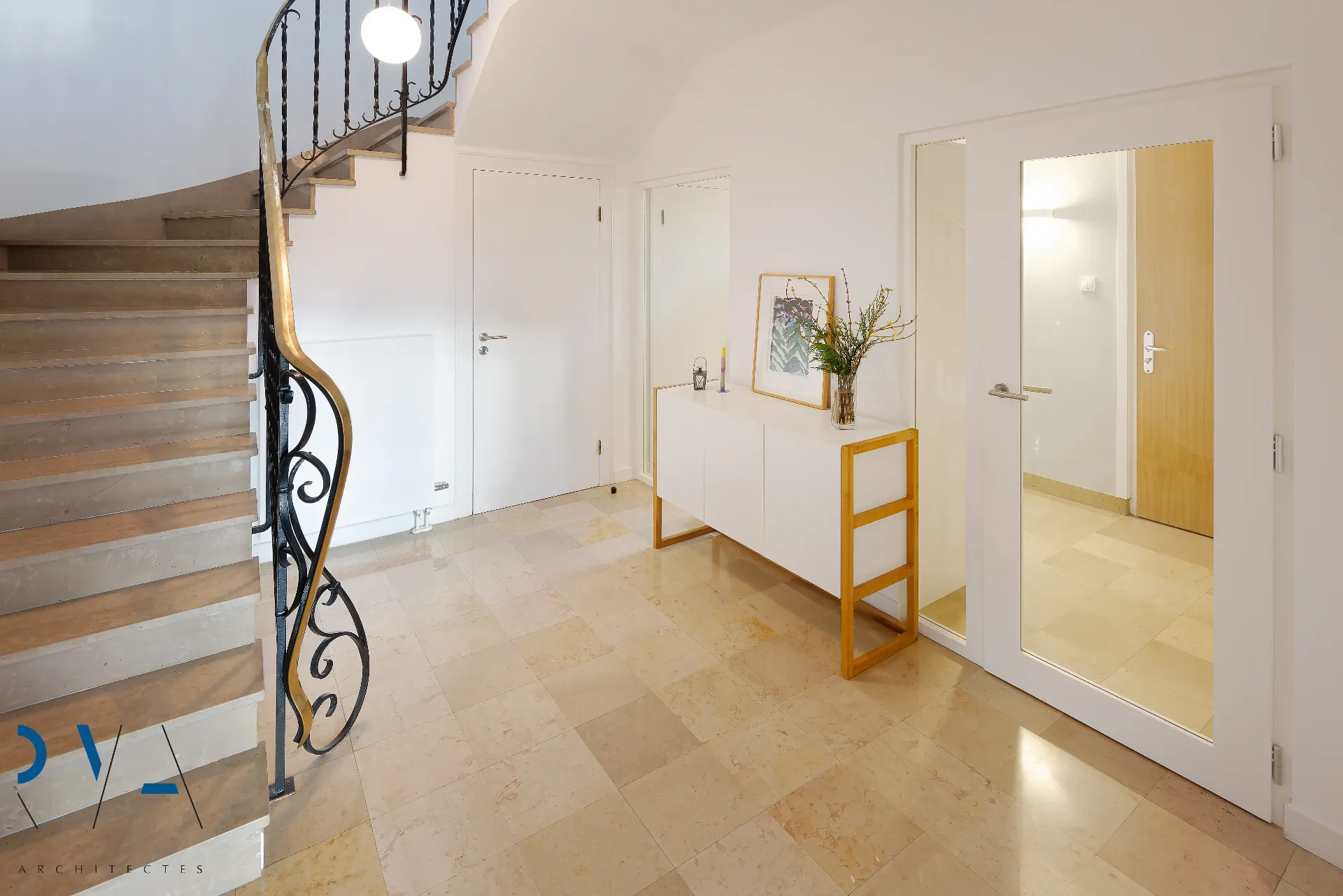 La lumière pénètre au cœur de la maison, révélant l'escalier et les matériaux nobles